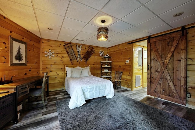 162 Grayson Pt, Blue Ridge, GA 30513 - bedroom featuring a barn door, wood finished floors, wooden walls, connected bathroom, and a drop ceiling