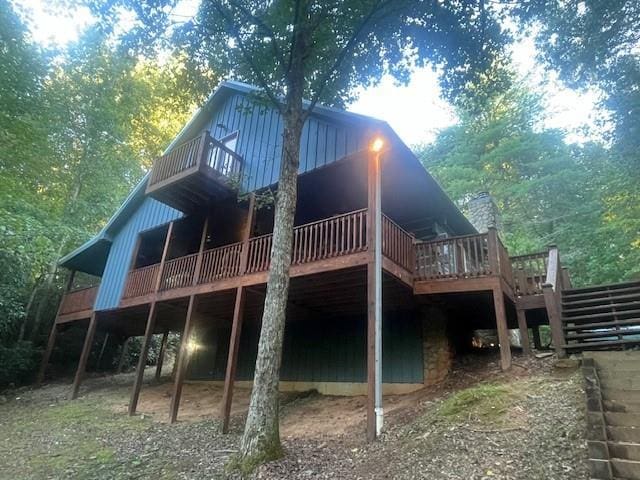 rear view of property featuring a forest view and a wooden deck