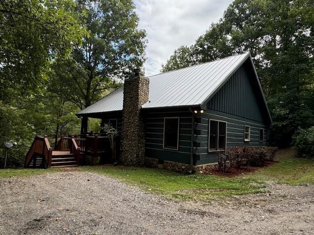 view of home's exterior with a deck, metal roof, and a chimney