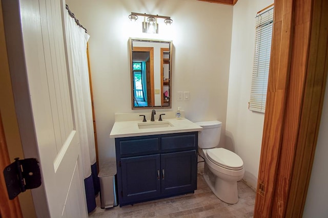 bathroom featuring a wealth of natural light, vanity, wood-type flooring, and toilet