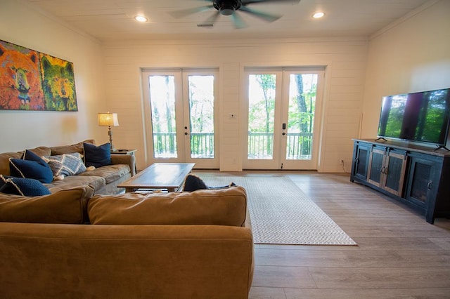 living room with light wood-type flooring, french doors, ceiling fan, and crown molding