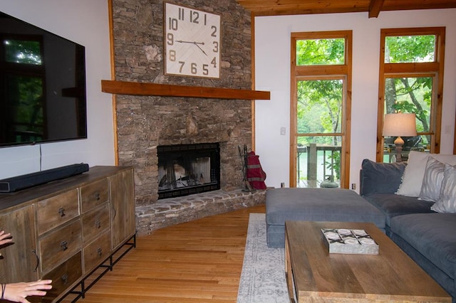 living room featuring a fireplace, light hardwood / wood-style floors, and beamed ceiling