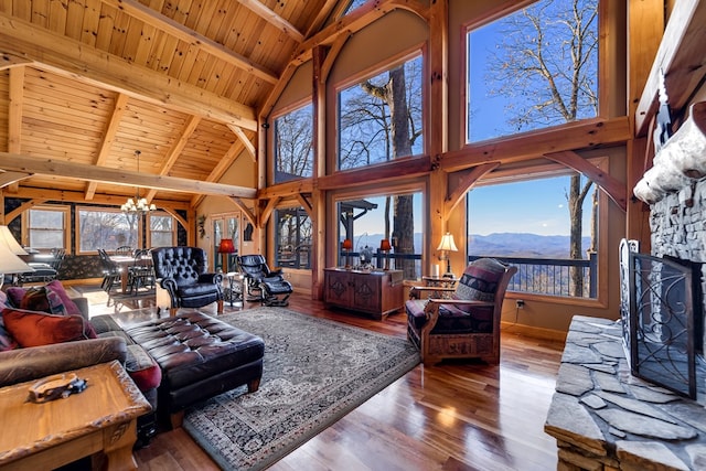 living room with a mountain view, wooden ceiling, a stone fireplace, hardwood / wood-style flooring, and a chandelier