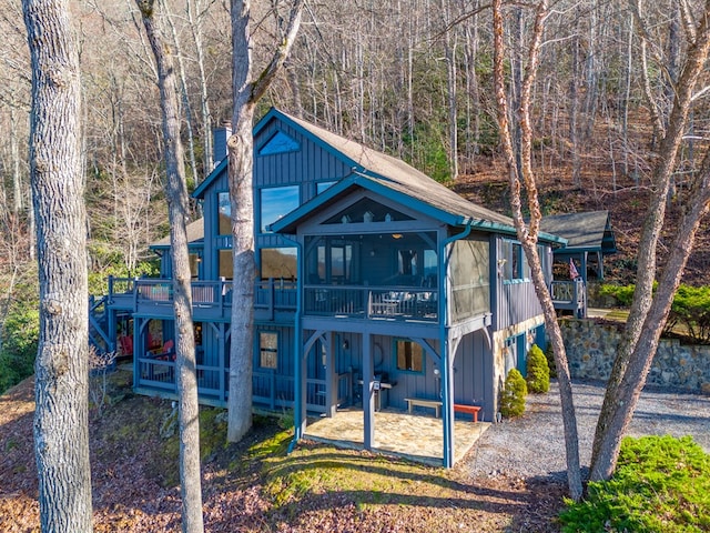 rear view of property with a wooden deck, a patio area, and a sunroom