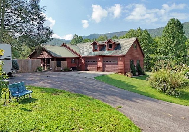 cabin with a front lawn, a mountain view, and a garage