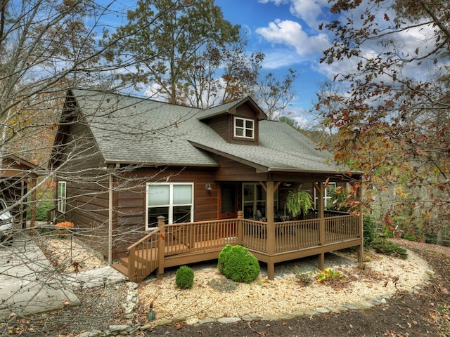 view of front of house featuring a wooden deck and roof with shingles