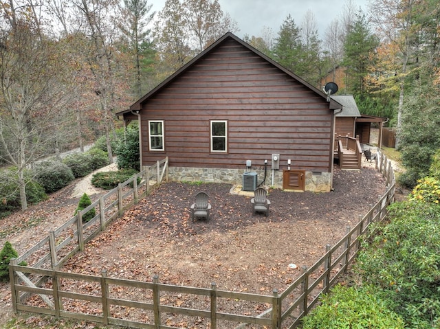 view of side of home featuring crawl space, fence, and central AC unit