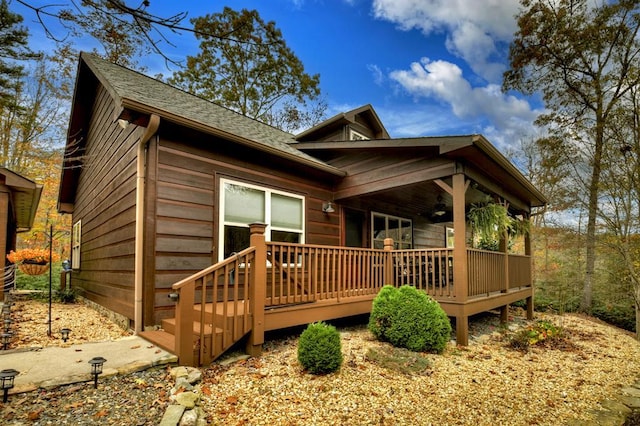 exterior space with a deck and roof with shingles