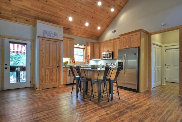 kitchen featuring stainless steel appliances, a breakfast bar, dark wood-style flooring, visible vents, and a center island