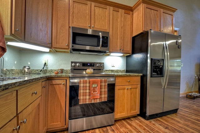 kitchen with stainless steel appliances, light wood-style flooring, and brown cabinets