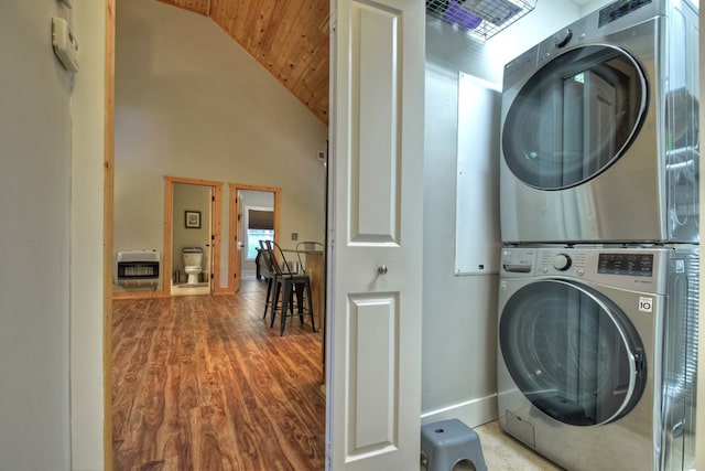 laundry room featuring laundry area, a high ceiling, wood finished floors, stacked washing maching and dryer, and heating unit