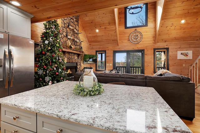 327 Dancing Trees Trl, Morganton, GA 30560 - kitchen with stainless steel fridge, a fireplace, wood walls, open floor plan, and light wood-style floors