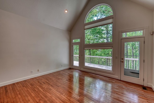 interior space with visible vents, baseboards, hardwood / wood-style floors, and high vaulted ceiling