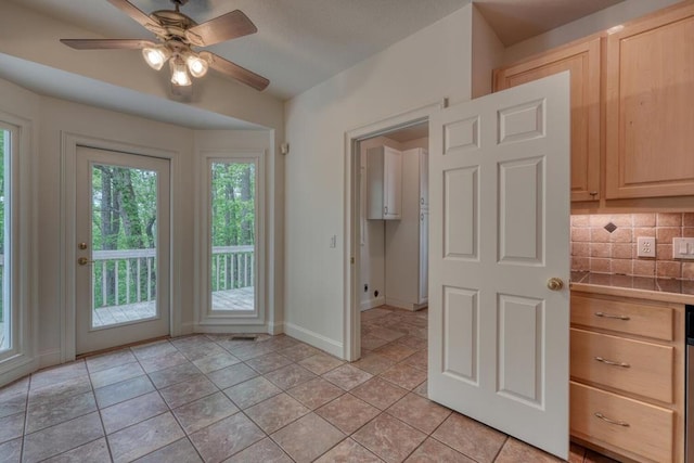 interior space with a ceiling fan, baseboards, and light tile patterned flooring