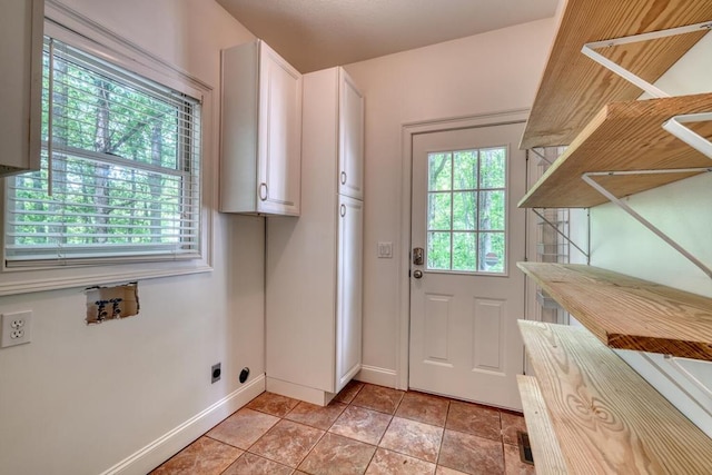 doorway with baseboards and light tile patterned floors