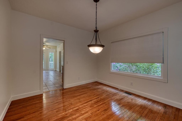 spare room featuring baseboards, wood-type flooring, and visible vents