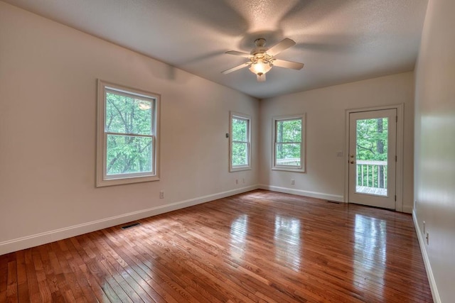unfurnished room with a ceiling fan, baseboards, visible vents, and hardwood / wood-style floors