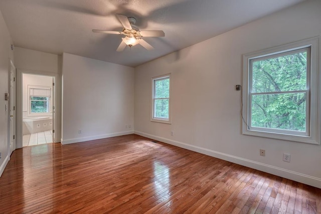 spare room featuring baseboards, wood-type flooring, and a ceiling fan