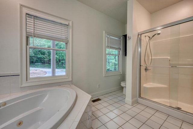 bathroom featuring tile patterned flooring, toilet, a shower stall, a healthy amount of sunlight, and a garden tub