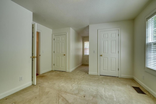 unfurnished bedroom featuring visible vents, carpet floors, and multiple windows