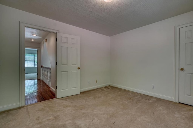 carpeted spare room featuring baseboards and a textured ceiling