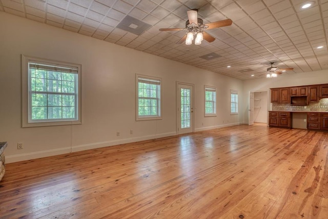 unfurnished living room featuring baseboards, light wood finished floors, and ceiling fan