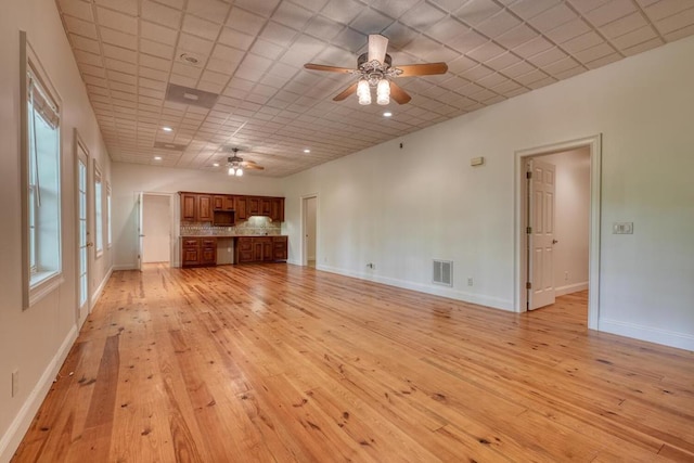 unfurnished living room with a ceiling fan, baseboards, visible vents, and light wood-type flooring