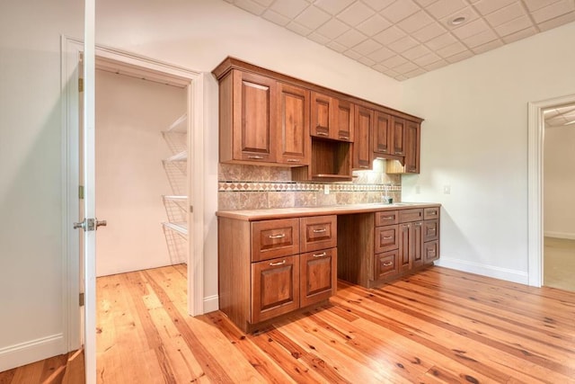 kitchen featuring light countertops, brown cabinets, light wood-type flooring, and tasteful backsplash