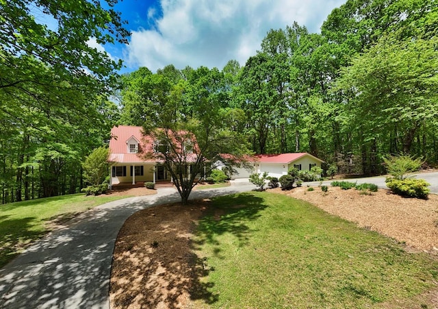 view of front of house featuring curved driveway, a porch, metal roof, and a front yard