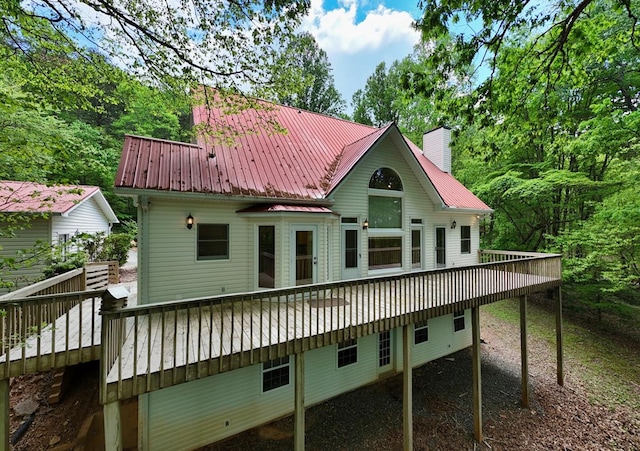 rear view of house with a chimney, a deck, and metal roof