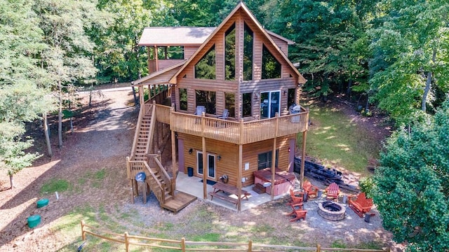 back of property with a fire pit, a deck, and a patio area