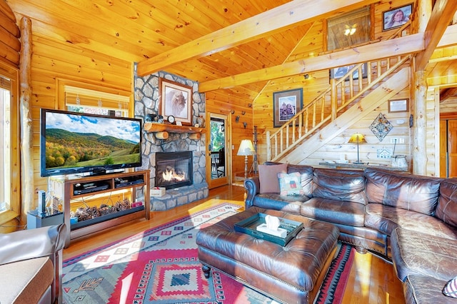 living room with wood-type flooring, vaulted ceiling with beams, a fireplace, wood ceiling, and wooden walls