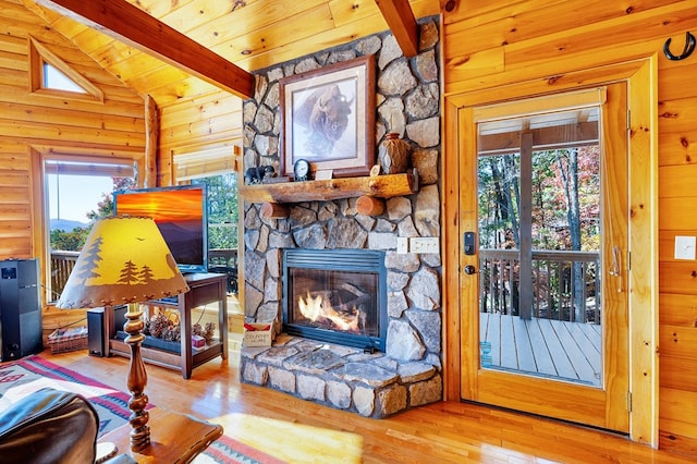 living room with a stone fireplace, lofted ceiling with beams, plenty of natural light, and hardwood / wood-style floors