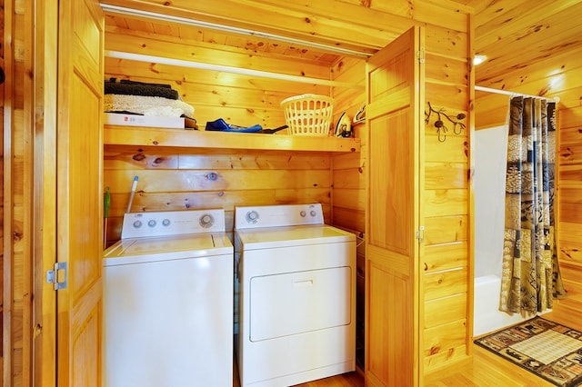 washroom with wood walls, washing machine and dryer, and light hardwood / wood-style flooring