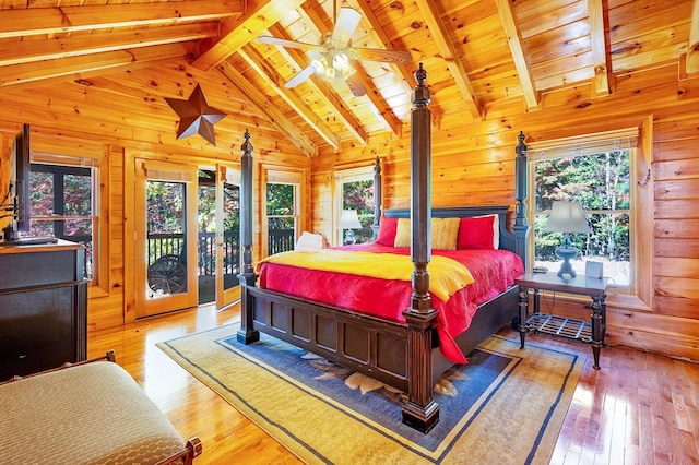 bedroom featuring wooden walls, multiple windows, wood-type flooring, and ceiling fan