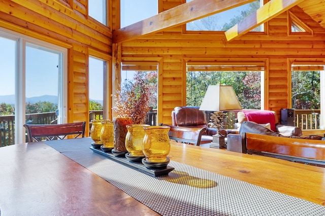 dining room with high vaulted ceiling, beam ceiling, a skylight, and log walls