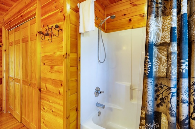 bathroom featuring wood walls, hardwood / wood-style flooring, and shower / bathtub combination with curtain