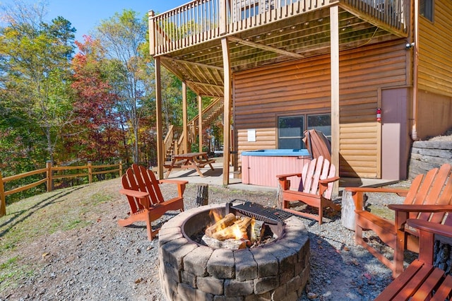 view of patio / terrace featuring a hot tub, a fire pit, and a deck