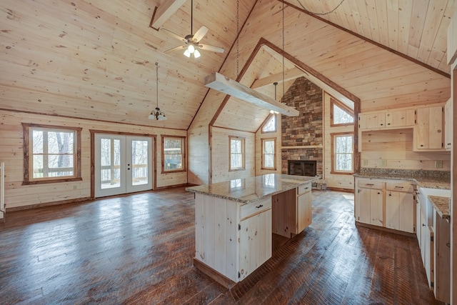 kitchen featuring a center island, beam ceiling, wood ceiling, light stone counters, and dark wood-type flooring