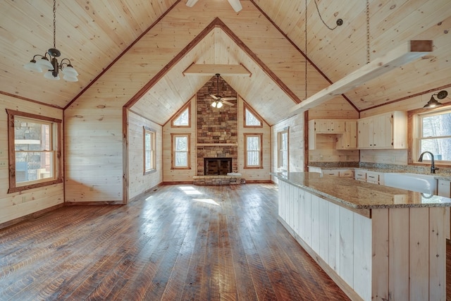 kitchen with light stone counters, pendant lighting, wood ceiling, sink, and dark hardwood / wood-style floors