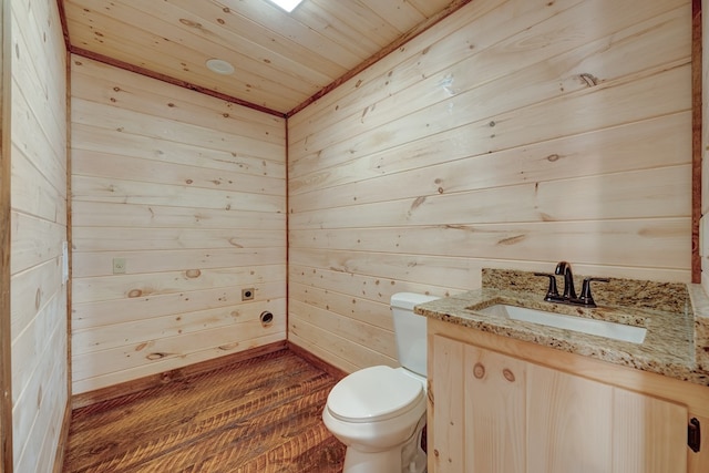 bathroom featuring toilet, wooden ceiling, wood-type flooring, vanity, and wooden walls