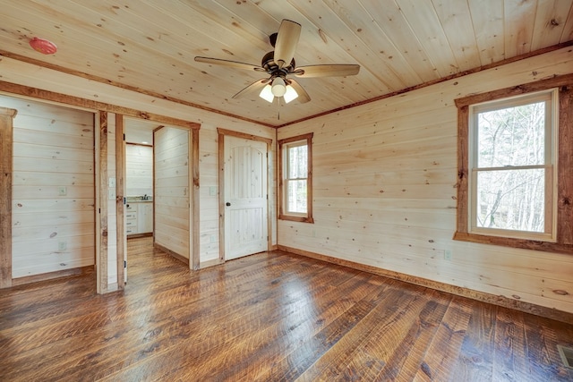 unfurnished room with ceiling fan, wood ceiling, dark hardwood / wood-style floors, and wooden walls