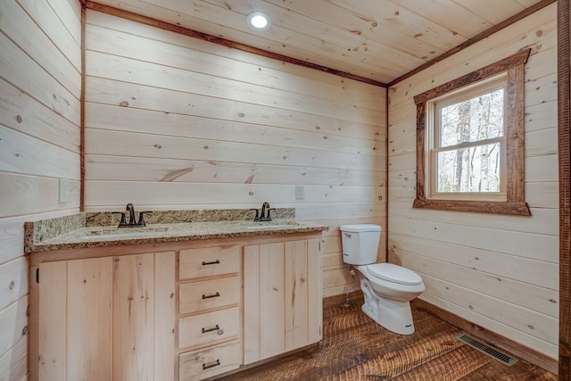 bathroom featuring toilet, vanity, wooden walls, and wood-type flooring