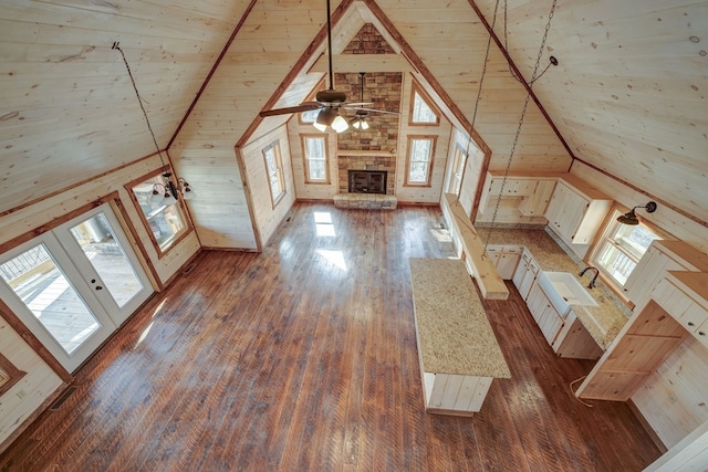 additional living space with a stone fireplace, dark wood-type flooring, high vaulted ceiling, wooden walls, and wood ceiling