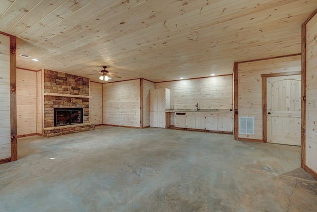 unfurnished living room featuring wooden ceiling, a stone fireplace, and wooden walls