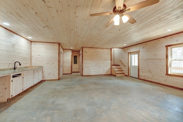 interior space featuring ceiling fan, sink, wood ceiling, and wood walls