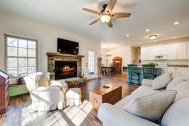 living room with ceiling fan, a fireplace, and dark hardwood / wood-style flooring