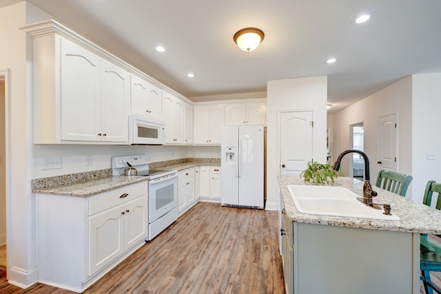 kitchen featuring white cabinetry, sink, white appliances, and a kitchen bar