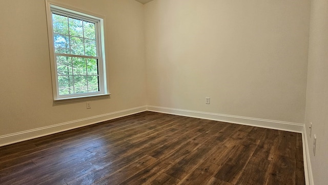spare room featuring dark wood-style flooring and baseboards