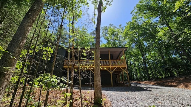 back of house featuring gravel driveway and a deck